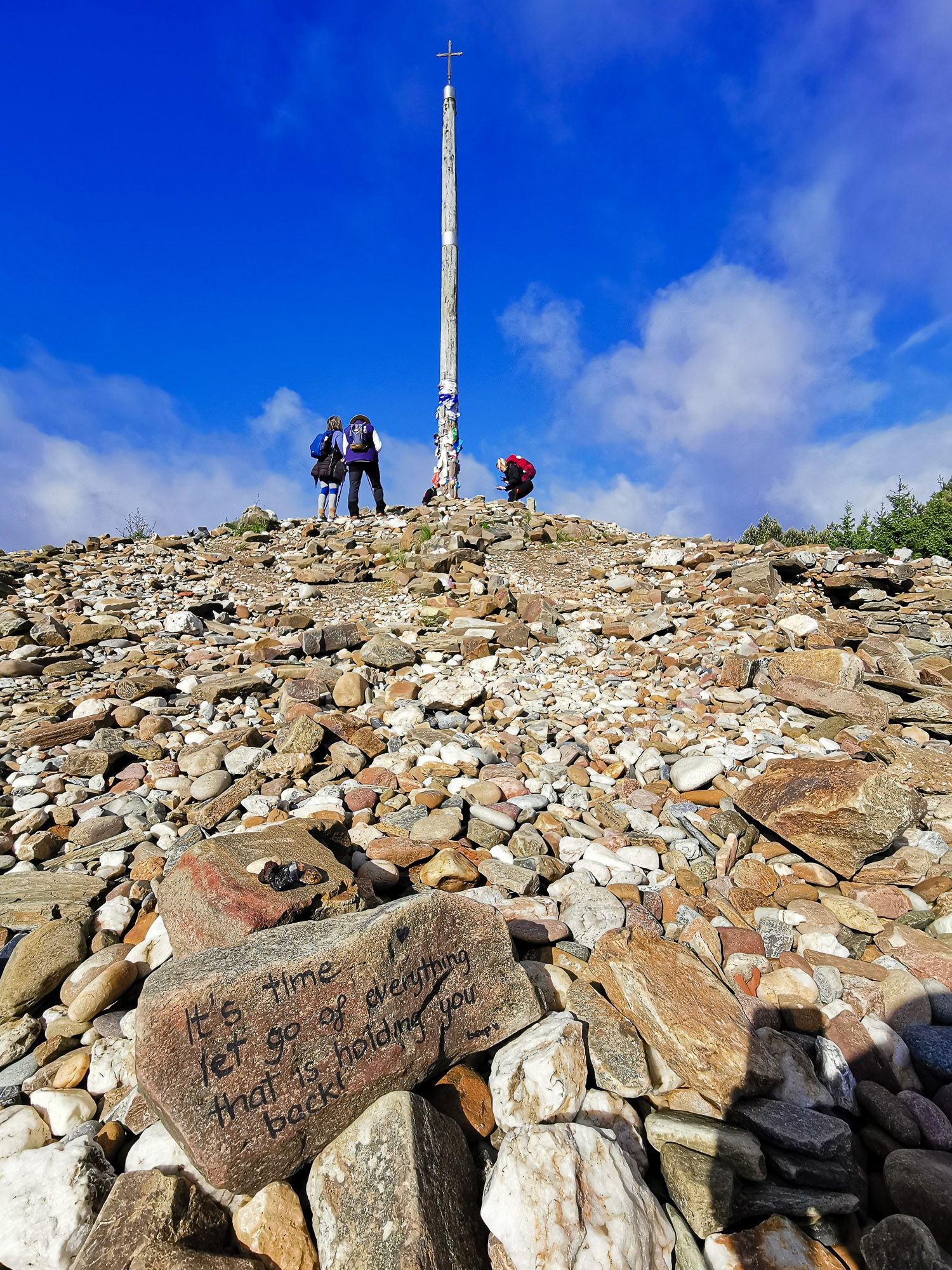 Cruz de Ferro ไม้กางเขนอยู่บนยอดเนิน รอบ ๆ เป็นหินรูปร่างต่าง ๆ 