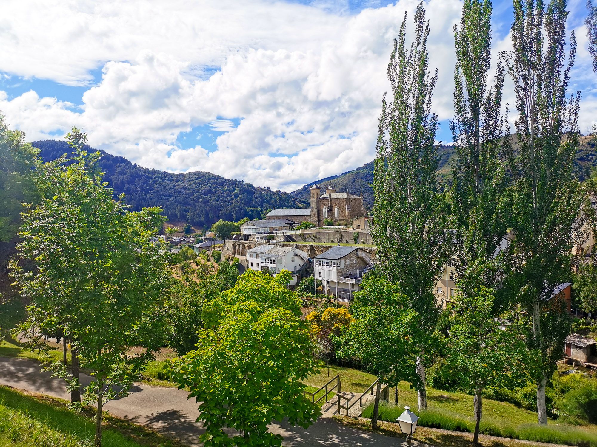 Villafranca del Bierzo มีโบสถ์อยู่กลางเมือง ล้อมรอบด้วยต้นไม้ และภูเขา