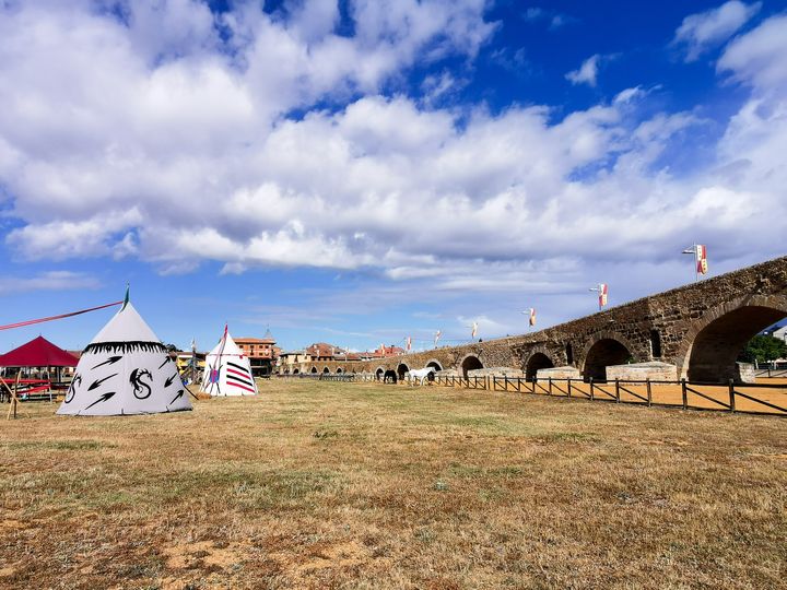 สะพาน El Paso Honroso อยู่ทางขวามือ ทางซ้ายมือมีการตั้งเต๊นท์แบบยุคอัศวิน