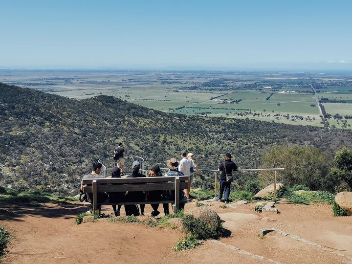คนนั่งชมวิวบนเก้าอี้ไม้ บนจุดชมวิวใกล้ยอด Flinders Peak